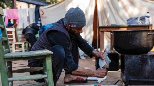 Abu Jaafar, a 44-year-old Syrian man, sets fire at a stove in front of his tent in a makeshift camp ...