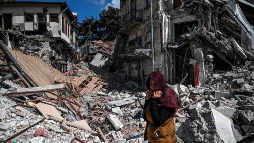 TOPSHOT - A woman stands among the rubble of collapsed buildings in Hatay on March 6, 2023, one ...