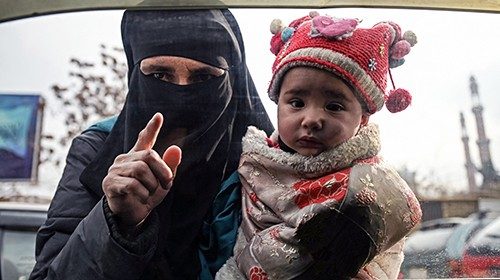 TOPSHOT - A woman carries a child as she begs from commuters in a car in Kabul on December 26, 2021. ...