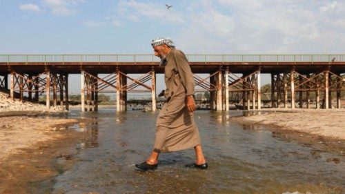 A man crosses the Abu Lehya river, which suffers from drought-induced drop in the water levels, in ... A man crosses the Abu Lehya river, which suffers from drought-induced drop in the water levels, in ...