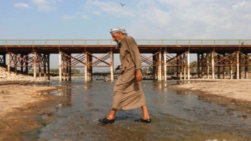 A man crosses the Abu Lehya river, which suffers from drought-induced drop in the water levels, in ...