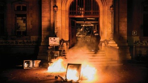 A police officer attempts to extinguish flames at the entrance of the town hall of the 4th ...
