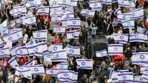 epa10530561 People hold Israeli flags as they march during a protest against the government's ...