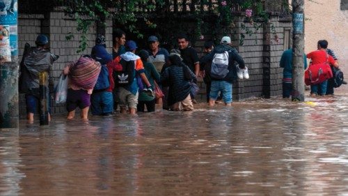 People wade through water flooding the main access road to Lima following heavy rains in Chaclacayo, ...