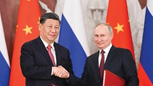 epa10536292 Chinese President Xi Jinping and Russian President Vladimir Putin shake hands after ...