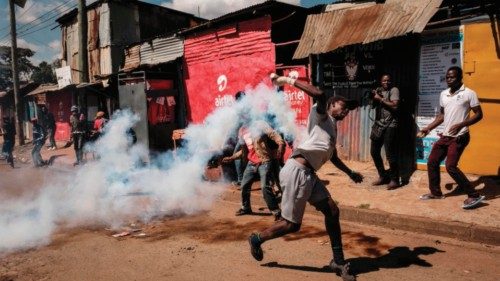TOPSHOT - A protester throws back a teargas canister towards police officers on the street during a ...