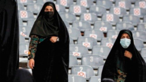 Iranian policewomen stand guard as women football fans wave Iranian national flags as they cheer for ...