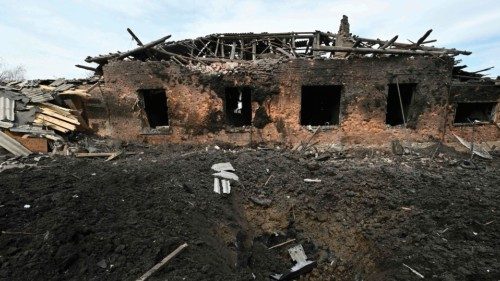 This photograph shows a crater in front of a damaged house after a military strike on the town of ...