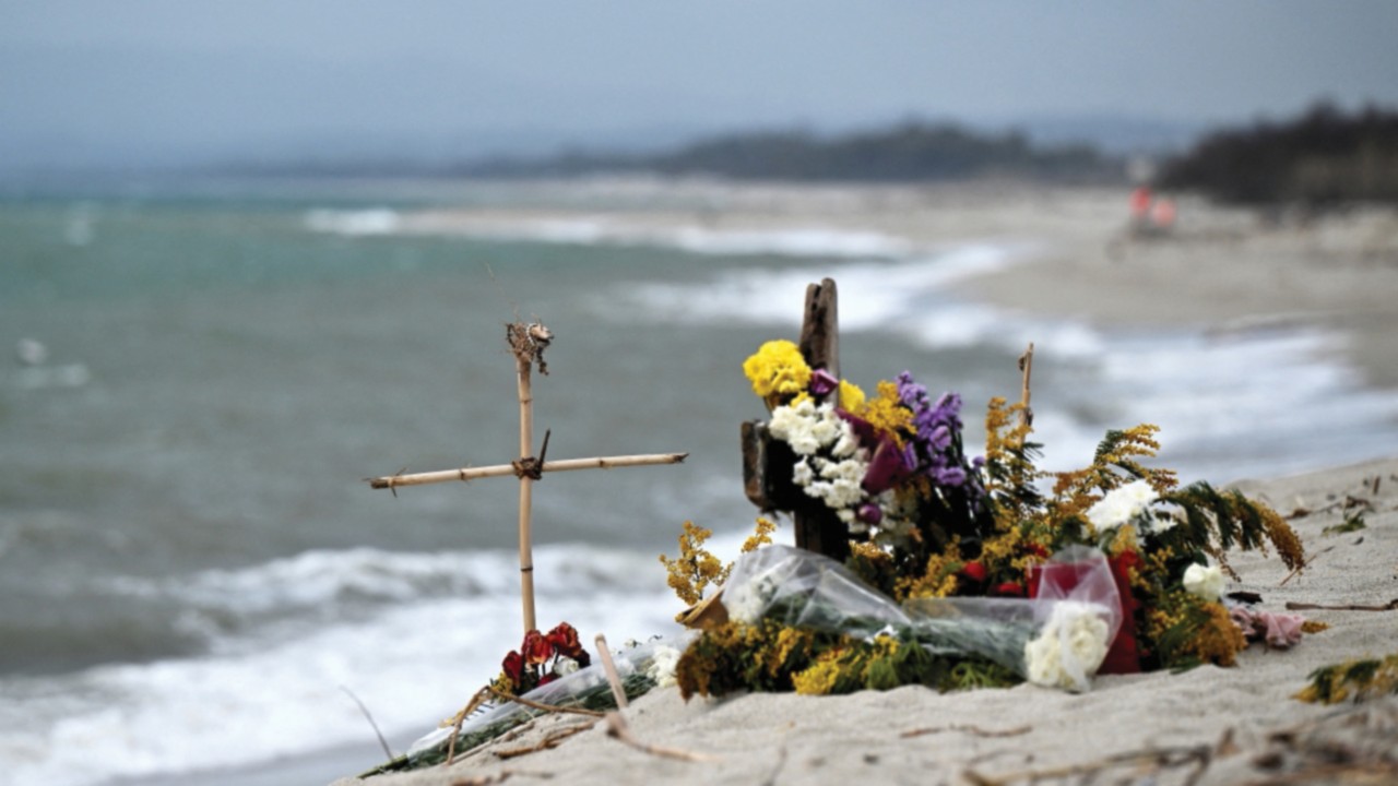 This photograph taken on March 9, 2023, shows flowers and crosses set as a memorial on a beach near ...