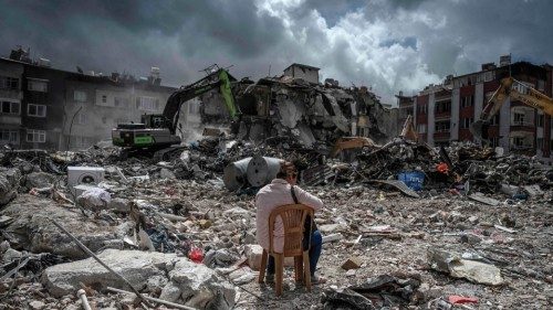 TOPSHOT - Emine Burc sits on a chair near where her house stood as the rubble of collapsed buildings ...