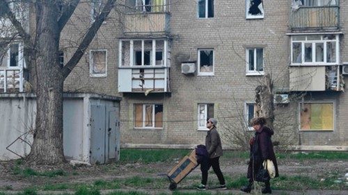 Local residents walk past a damaged residential building in the frontline town of Avdiivka, Donetsk ...