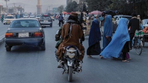 FILE PHOTO: A group of women wearing burqas crosses the street as members of the Taliban drive past ...