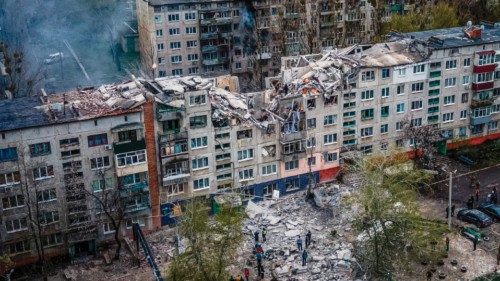 TOPSHOT - This aerial view shows rescuers on top of a partially destroyed residential building, ...
