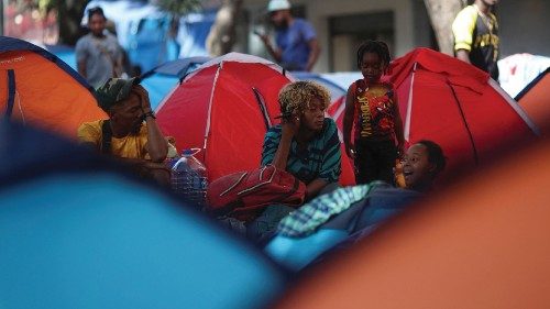Migrants, mostly from Haiti, gather outside their tents at the Giordano Bruno park as they wait for ...