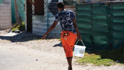A woman carries a bucket of water which she filled at a nearby tap in Zwelitsha, an informal ...