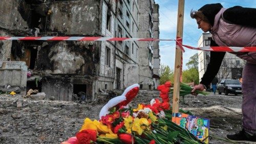 A woman lays flowers in front of a damaged multistory residential building, where a Russian strike ...