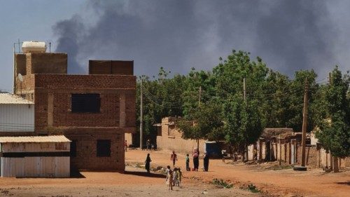 People walk as smoke billows in the background during fighting in the Sudanese capital Khartoum, on ...