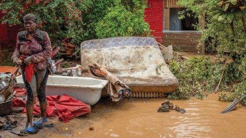 A resident salvages her household items washed away following rains that triggered flooding and ...
