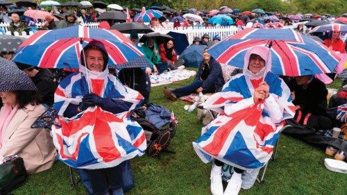 TOPSHOT - Well-wishers protect themselves against the rain as they wait along the route of the ...