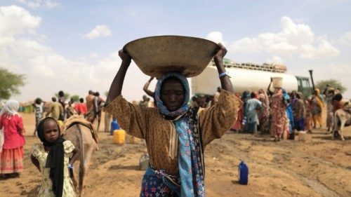 A Sudanese refugee woman, who fled the violence in Sudan's Darfur region, carries a basin of water ...