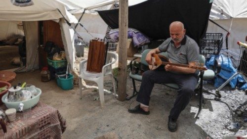 epa10610838 Ergun Akin, an earthquake victim, plays a baglama, a Turkish folk instrument at his tent ...