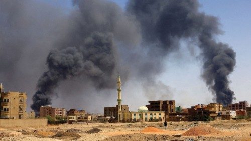 FILE PHOTO: A man walks while smoke rises above buildings after aerial bombardment, during clashes ...