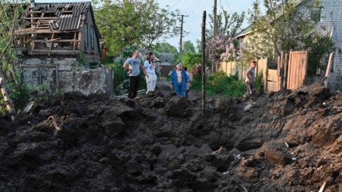 TOPSHOT - Local residents look at a crater after a missile strike in Tsirkuny village, Kharkiv ...