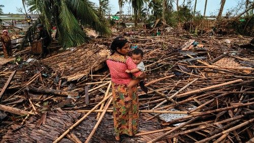 (FILES) A Rohingya woman carries her baby next to her destroyed house at Basara refugee camp in ...