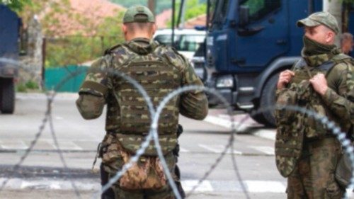 NATO Kosovo Force (KFOR) soldiers stand guard behind razor wire fence in the town of Zvecan, Kosovo, ...