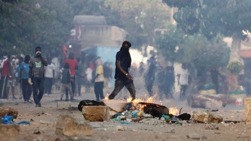 A supporter of Senegal opposition leader Ousmane Sonko walks near a burning barricade during clashes ...