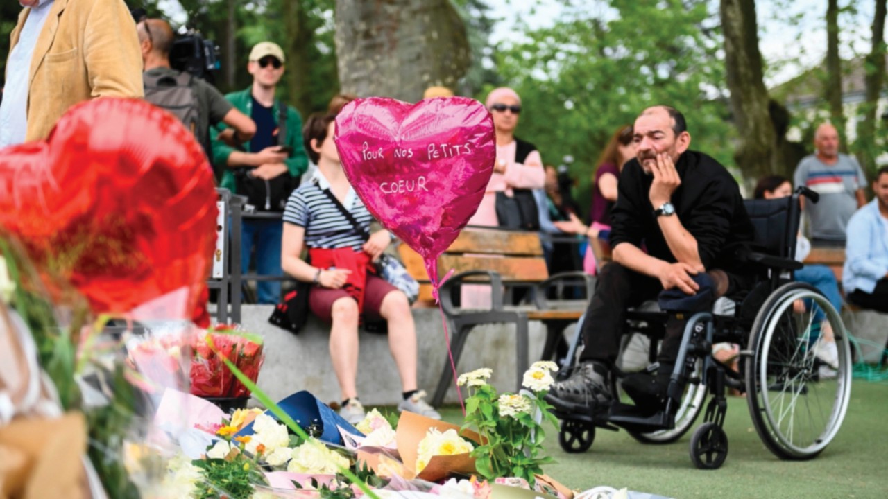 A balloon bearing a message 'For our sweethearts' is seen as people gather in front of flowers and ...