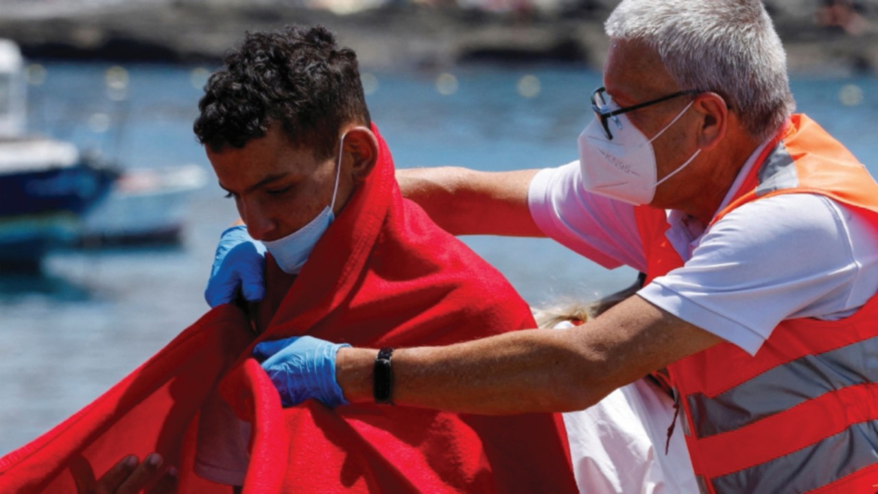 FILE PHOTO: A member of the Red Cross assists a migrant after disembarking from a Spanish coast ...