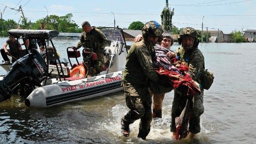 Ukrainian servicemen help to unload a disabled local resident from a boat during an evacuation from ...