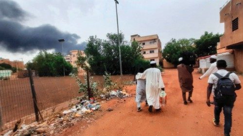 TOPSHOT - Smoke rises above buildings as people flee with some belongings, in Khartoum on June 10, ...