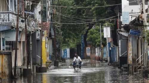 A man rides a motorcycle through a waterlogged street in Mandvi before the arrival of cyclone ...