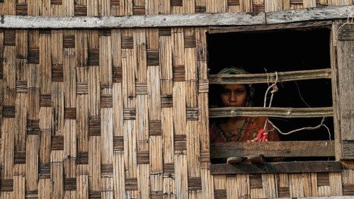 A girl looks out from a destroyed house at Ohn Taw Chay refugee camp in Sittwe on May 16, 2023, in ...