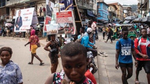TOPSHOT - People walk past campaign posters in Freetown on June 19, 2023. Sierra Leoneans will vote ...
