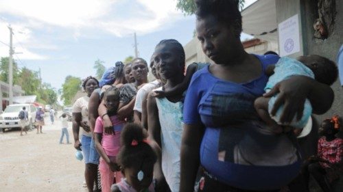 Women stand in line at the New Church of God of Deliverance camp for displaced people, which now ...