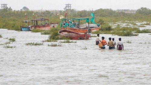 epa10696498 People wade through flooded coastal area to check their boats anchored near the Jakhau ...