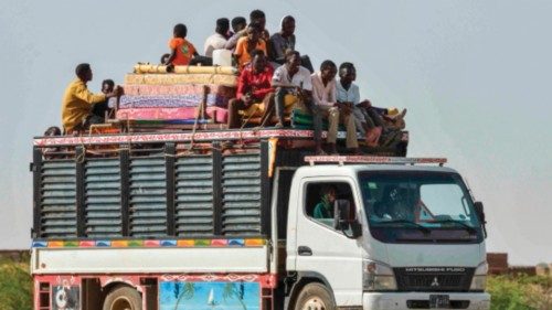 TOPSHOT - People ride with furniture and other items atop a truck moving along a road from Khartoum ...
