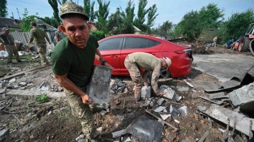 Ukrainian servicemen help to clear debris after an overnight Russian missile strike in the town of ...