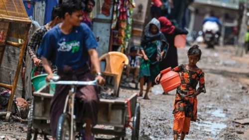 TOPSHOT - A Rohingya refugee girl gestures as she walks through a muddy street at a refugee camp on ...
