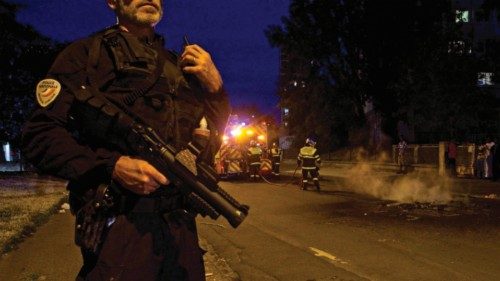 A police officer holds a flash ball as he stands next to firefighters during clashes on June 30, ... A police officer holds a flash ball as he stands next to firefighters during clashes on June 30, ...
