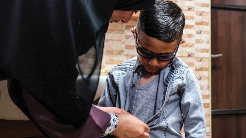 CORRECTION / Adam Abu al-Rob, a six-year-old Palestinian eye cancer patient, is assisted to dress up ...