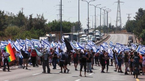 Demonstrators lift banners and flags as they block Highway 443 between Jerusalem and Tel Aviv, near ...