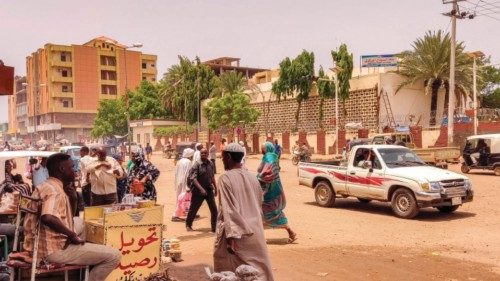 Pedestrians and vehicles move along a road outside a branch of the Central Bank of Sudan in the ...