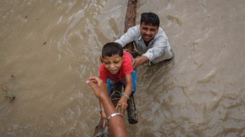 A man helps his son to climb onto a flyover under construction, after being displaced by the rising ...
