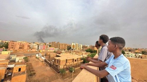 People watch as smoke rises during clashes between the army and the paramilitary Rapid Support ...