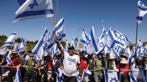 Demonstrators wave Israeli national flags as they march on the highway near the town of Mevasseret ...