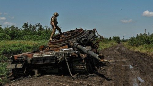 A Ukrainian serviceman inspects a destroyed Russian tank in the recently liberated village of ...